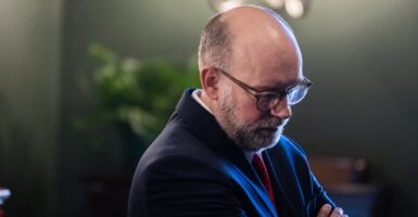 Russell Vought stands in a room with his arms folded.