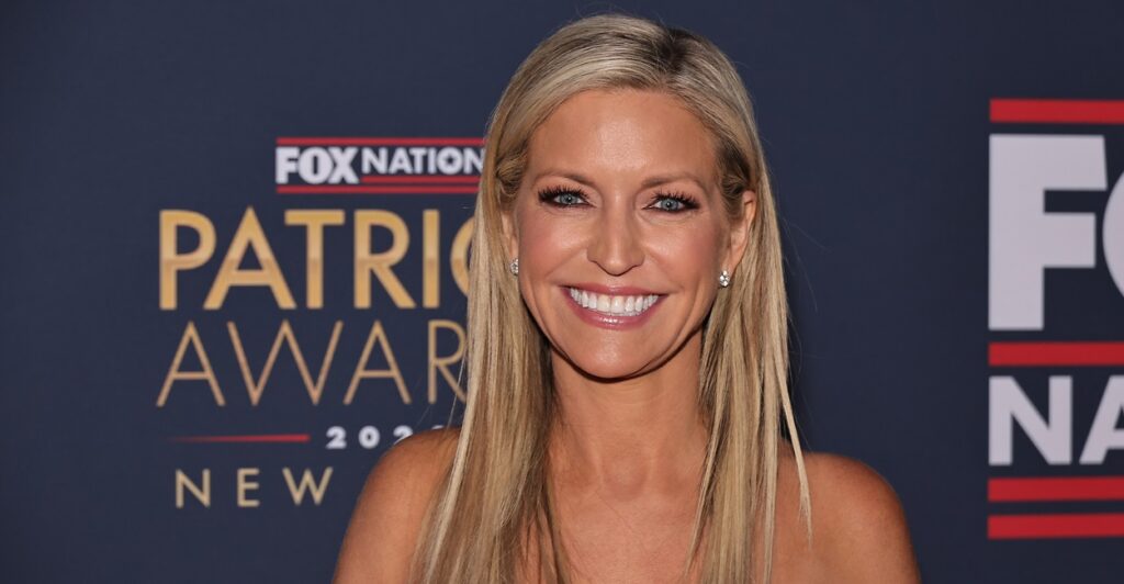Ainsley Earthardt smiles while standing on the red carpet of an awards show.