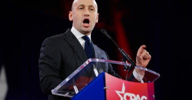 Stephen Miller in a dark suit and tie standing at a CPAC podium