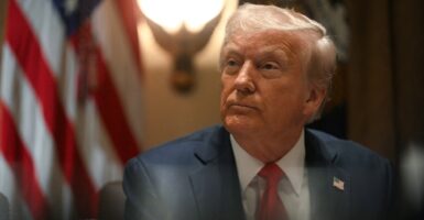 Donald Trump sits at his desk at the White House and looks to his left.