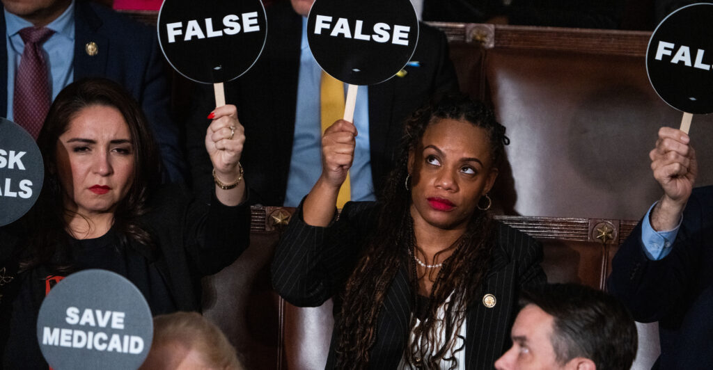 Reps. Summer Lee, D-Pa. (right) and Delia Ramirez, D-Ill., hold up signs as President Donald Trump delivered his address to a joint session of Congress in the House Chamber of the Capitol on Tuesday night.