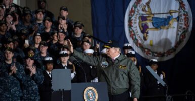 President Donald Trump waves after speaking to Navy and shipyard personnel aboard the nuclear aircraft carrier Gerald R. Ford at Newport News Shipbuilding in Newport News, Va., eight years ago this month on March 2, 2017. A large Virginia state flag hangs vertically on the wall at right.