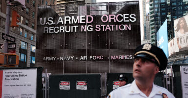 A police officer stands guard as demonstrators gather in New York City's Times Square near a military recruitment center to protest President Donald Trump's reinstatement of a ban on transgender individuals from the military on July 26, 2017.