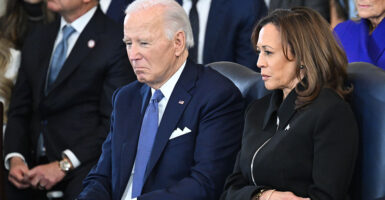 Former President Joe Biden wears a navy suit and sits next to former Vice President Kamala Harris, who wears a black jacket.