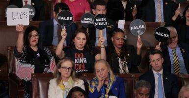 Democrats sit in seats and hold up signs protesting Donald Trump's speech.