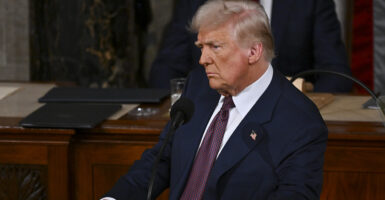 Donald Trump in a blue suit with an American flag pin looks skeptical