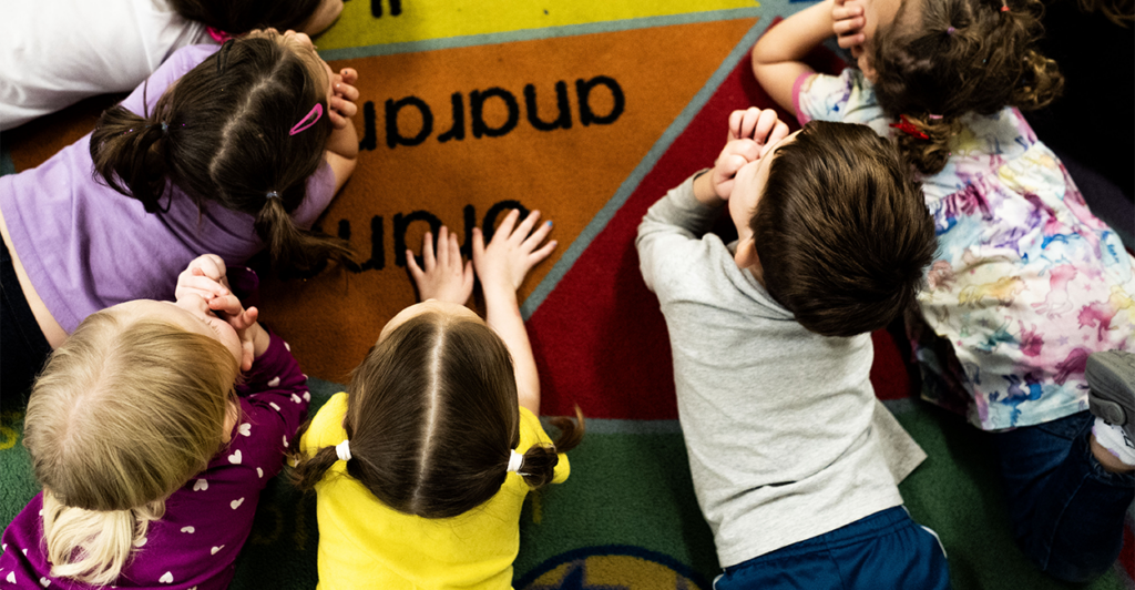 Pre-k children listen to their teacher in a school.