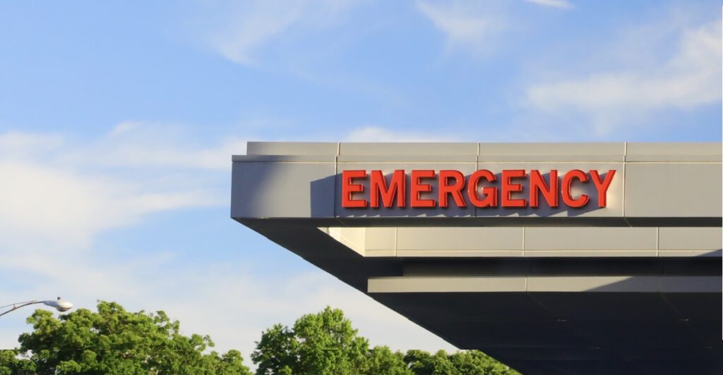 A sign in red lettering states "Emergency" on the roof of a building.