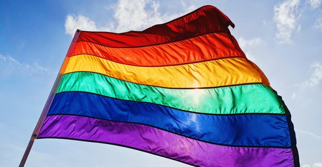 A gay pride flag flies in the wind.