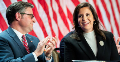 Speaker of the House Mike Johnson, R-La., and Rep. Elise Stefanik, R-N.Y., with a large U.S. flag as backdrop