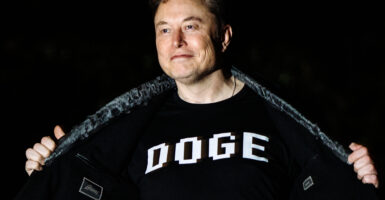 Elon Musk wears a garment sporting the acronym "DOGE" for the Department of Government Efficiency