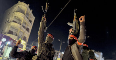 Masked armed forces of the new Syrian government raise their Kalashnikov rifles as they are being deployed to the coastal city of Latakia.