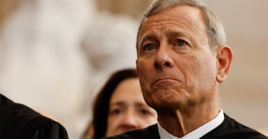Chief Justice John Roberts in a white collared shirt and black gown.