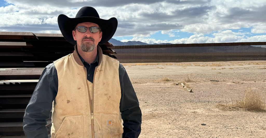 Rancher Russell Johnson stands in front of border wall panels that are waiting to be used to fill gaps in the border wall in Luna County, N.M.