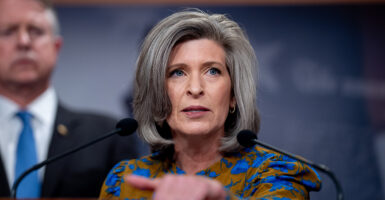 Joni Ernst in a red and blue blouse looking livid