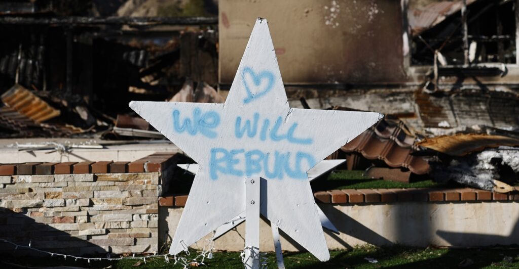 A handwritten sign posted in front of the ruins of the fires in Pasadena states they will rebuild.