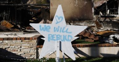 A handwritten sign posted in front of the ruins of the fires in Pasadena states they will rebuild.