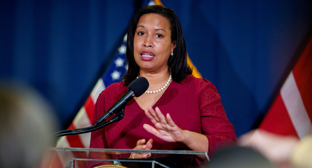 Muriel Bowser in a red blouse in front of American flags