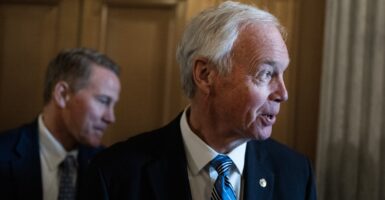 Ron Johnson looks to his left while in a hallway talking to people.