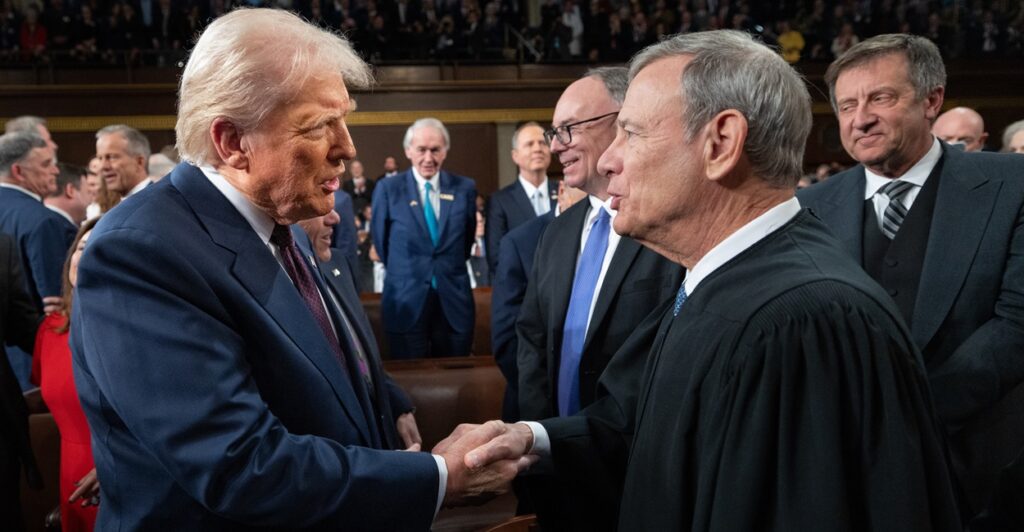 Donald Trump and John G. Roberts, Jr. shake hands while standing next to each other.
