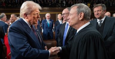 Donald Trump and John G. Roberts, Jr. shake hands while standing next to each other.
