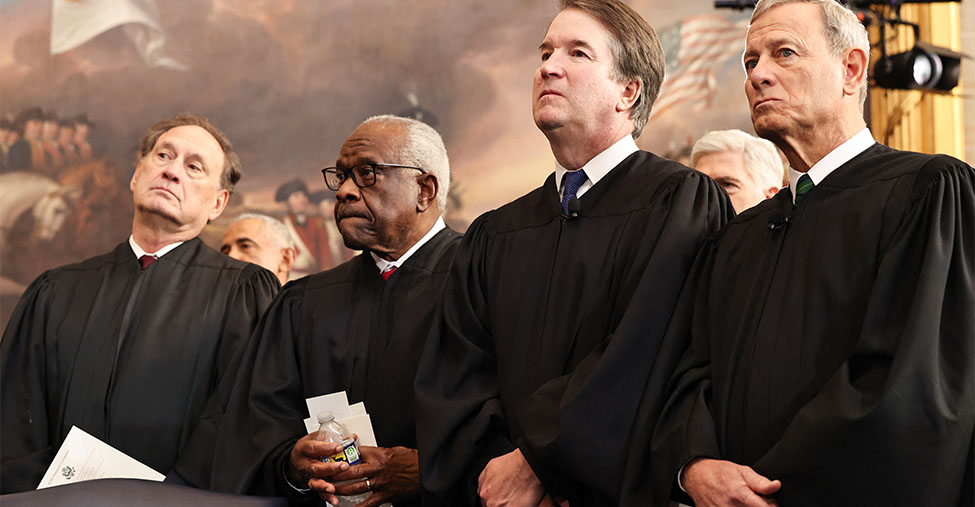 Justices Samuel Alito, Clarence Thomas, Brett Kavanaugh, and John Roberts stand in black robes.