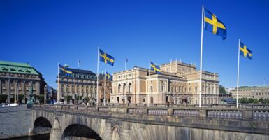 Swedish flags fly on a sunny day on a bridge in Sweden.
