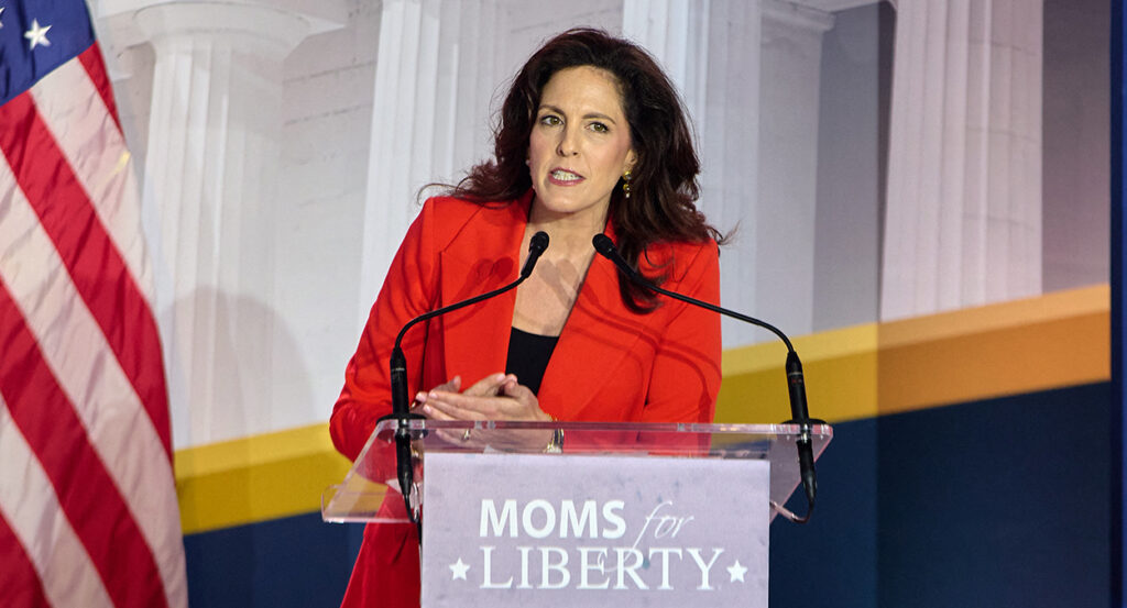 Tiffany Justice in a red blazer behind a Moms for Liberty podium