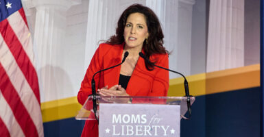 Tiffany Justice in a red blazer behind a Moms for Liberty podium