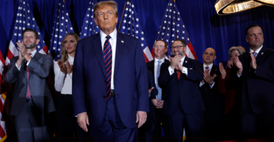 With American flags as a backdrop, Donald Trump appears with campaign officials and family members at a January 2024 campaign event in New Hampshire.