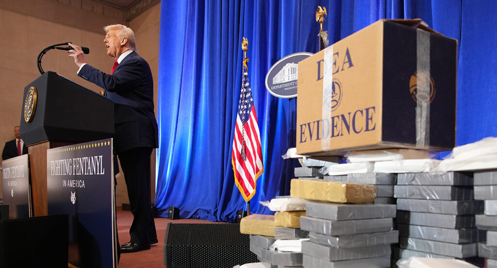 President Trump speaks in a suit near a large cache of DEA evidence of fentanyl