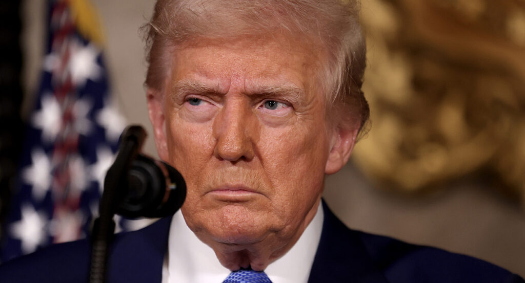 President Donald Trump gazes into the camera in a suit