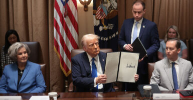 President Donald Trump holds up an executive order he signed.