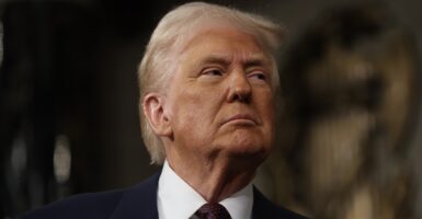 Donald Trump looks out at a gallery of people while standing and giving a speech.