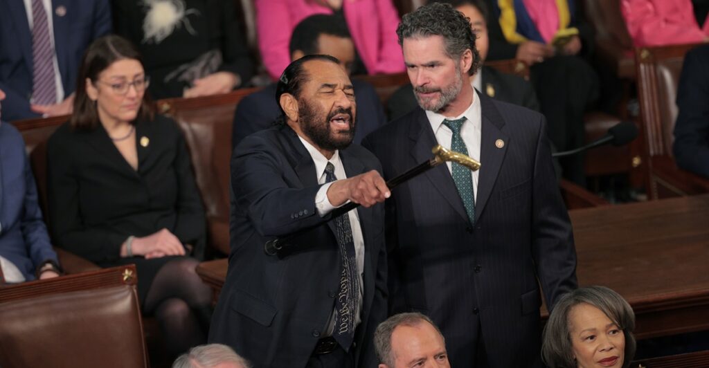 Al Green is standing and motioning with a cane in his left hand.