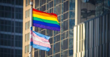 The transgender flag flies underneath the gay pride flag.