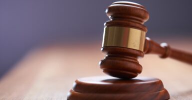 A gavel is displayed on a wooden table.