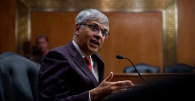 Jay Bhattacharya sits before a microphone and gestures with his right hand as he speaks.