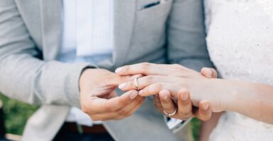 A man puts a wedding ring on a woman's finger.