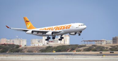 A plan has its wheels down as it prepares to land on a runway.