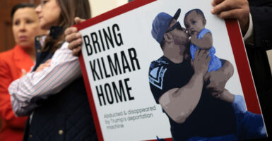 Protester holds sign reading "Bring Kilmar Home." Sign features the deported MS-13 member kissing a baby.