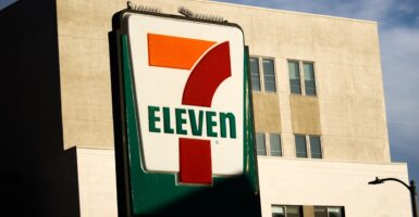 A 7Eleven log stands in the daylight in front of a store.