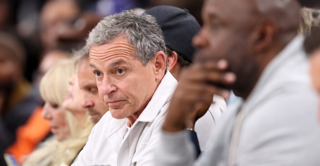 Bob Iger sits in the front row of a NBA playoff basketball game and looks straight ahead.