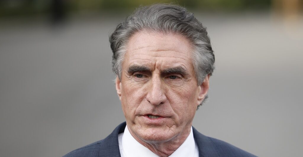 Doug Burgum is standing and stares ahead as he talks to reporters at the White House.