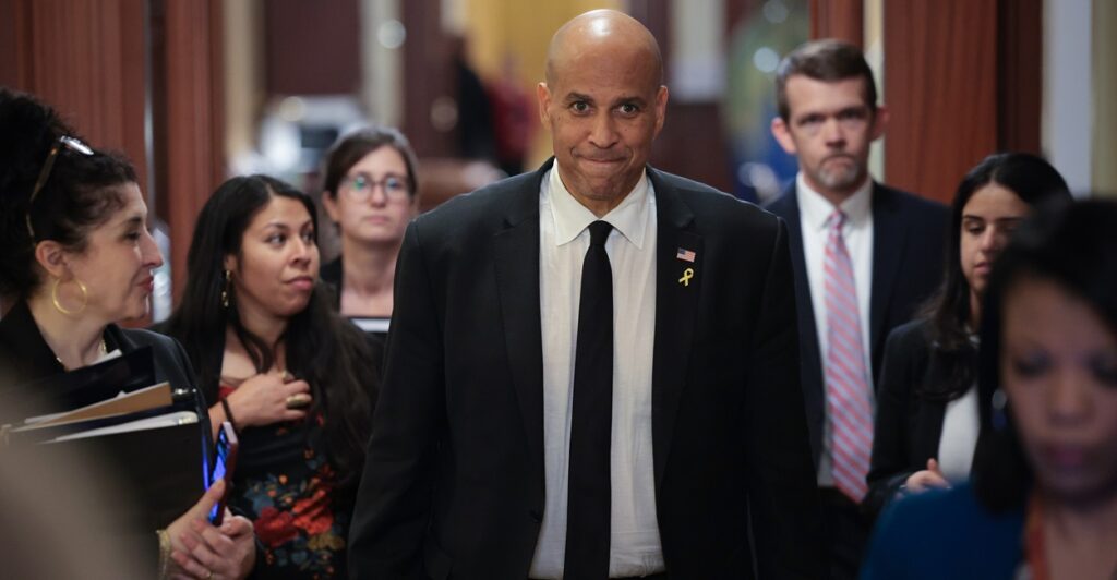 Cory Booker stands in a hallway with his hands by his side.