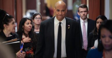 Cory Booker stands in a hallway with his hands by his side.