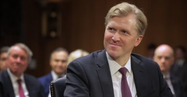 Elbridge Colby sits at a table and looks to his left.