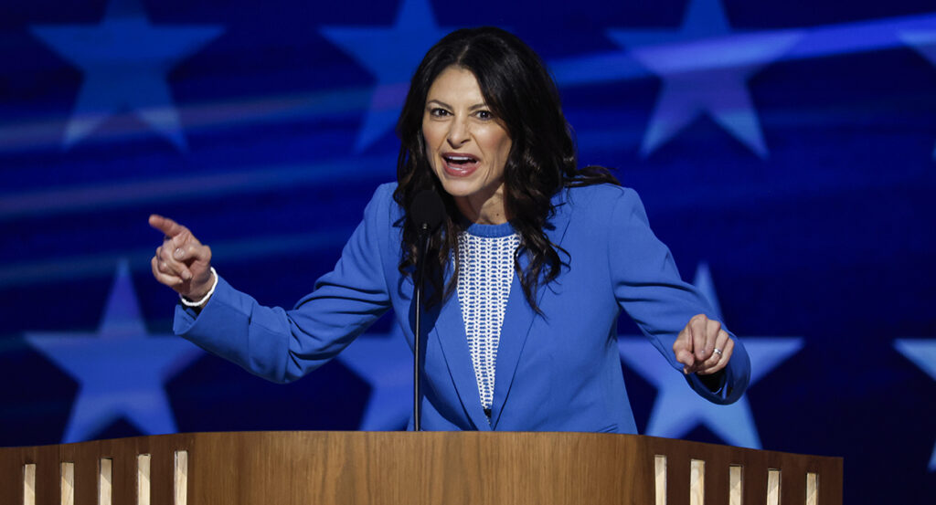 Michigan AG Dana Nessel in A blue suit on stage with a microphone