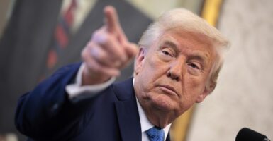 Donald Trump stands and uses his right hand to point to someone in a crowd.