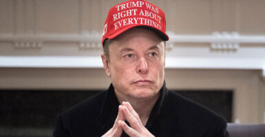 Elon Musk in black wears a red hat reading "Trump was right about everything"